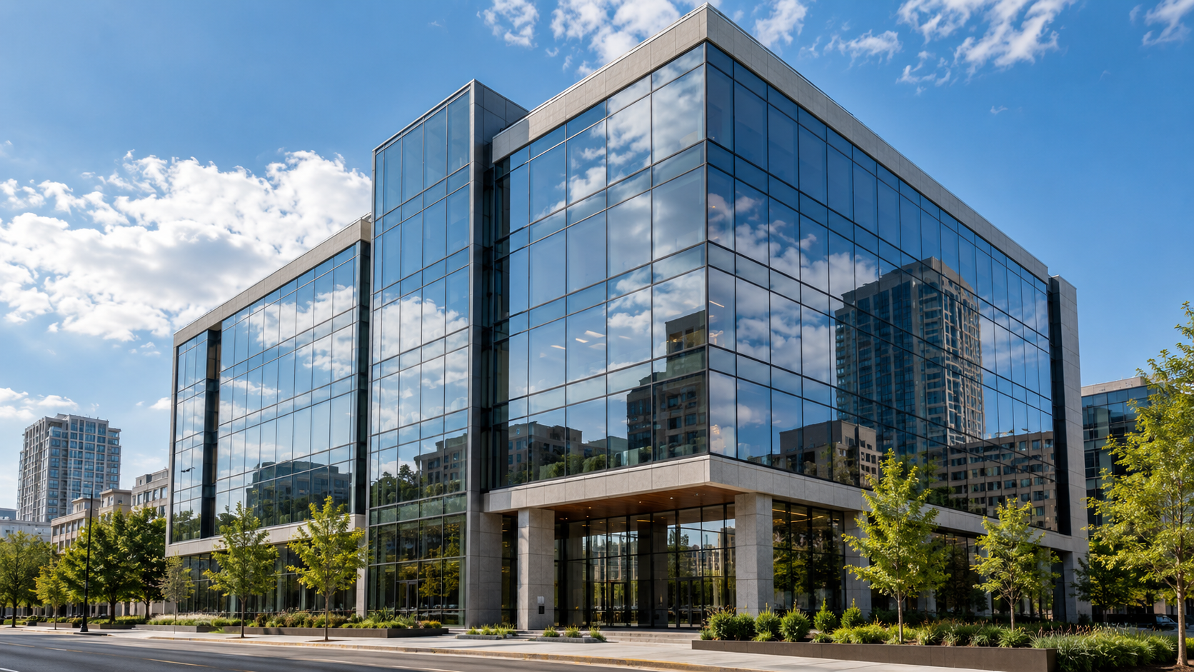 Reflective window film on an office building facade reflecting clouds and nearby buildings.